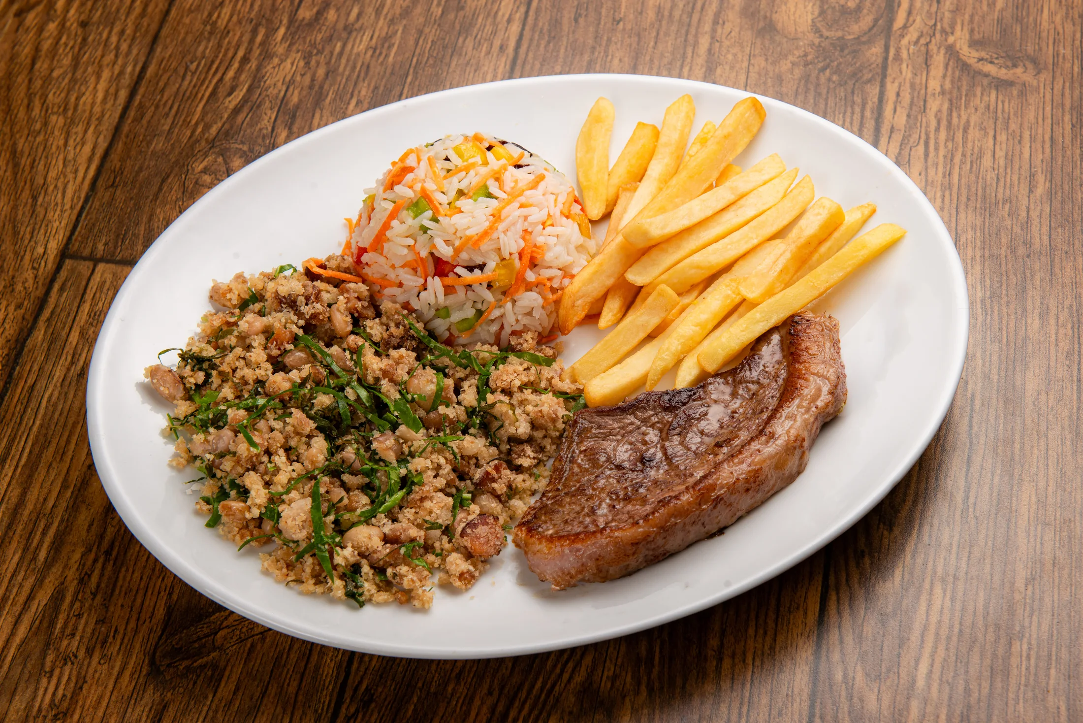 Picanha mineira especial grelhada ao molho madeira com feijão-tropeiro, arroz à grega e batatas fritas douradas sobre mesa de madeira rústica